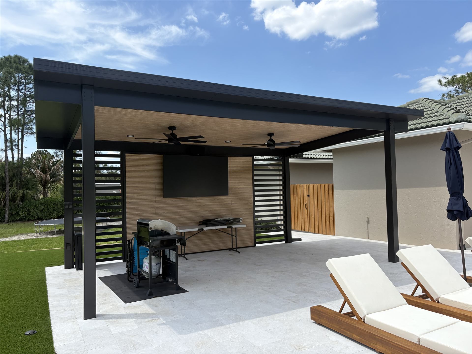 Modern black aluminum pergola with louvered privacy screens and outdoor lounge seating, built by Big Al's Aluminum