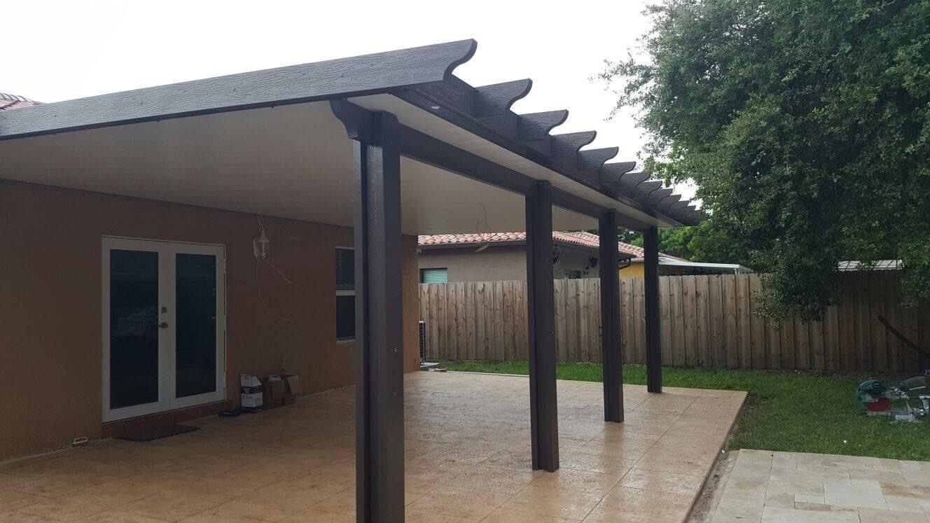 Bronze aluminum patio cover with decorative rafter tails over a stamped concrete patio