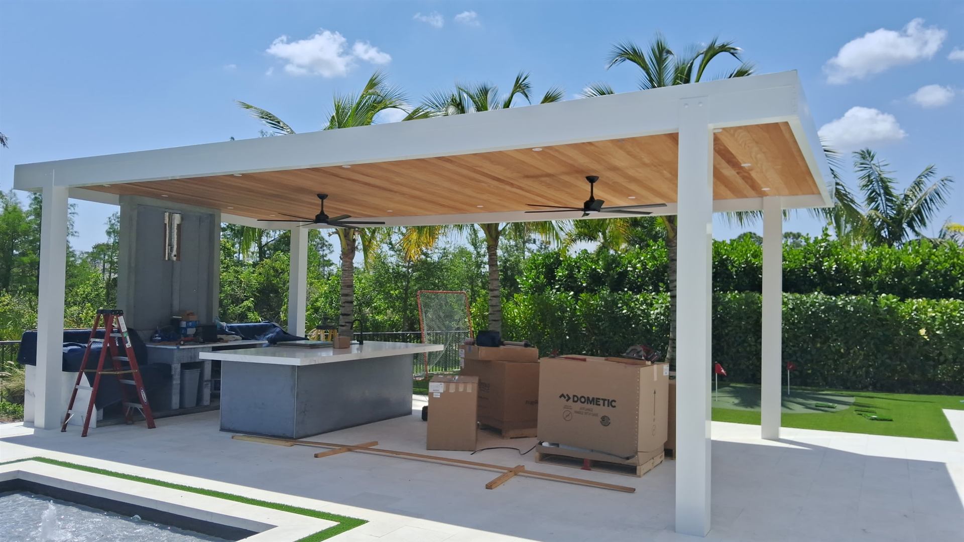 Aluminum pergola with wood ceiling over an outdoor kitchen and lounge
