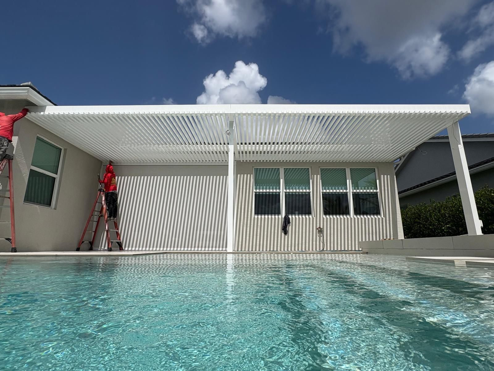 Louvered aluminum pergola over a swimming pool being installed by the Big Al’s crew
