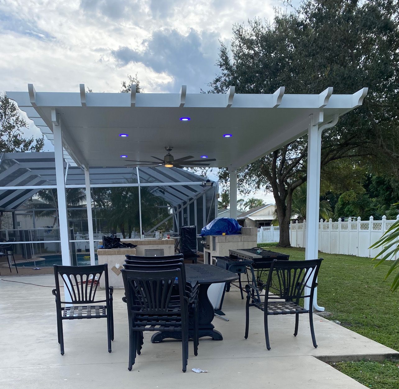 White aluminum pergola with scalloped rafter tails and integrated LED downlights