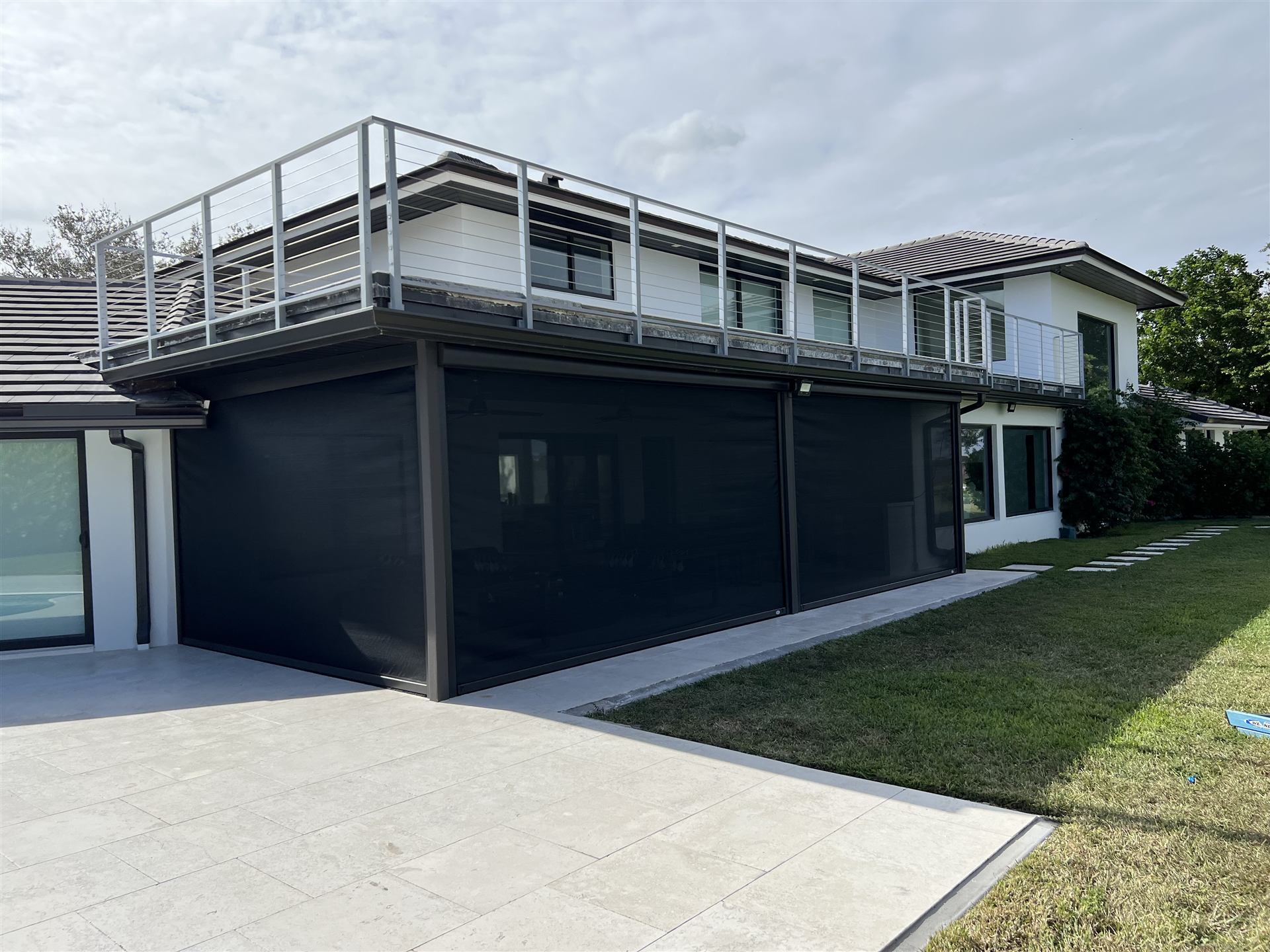 Electric roll-down screens deployed on a modern two-story home