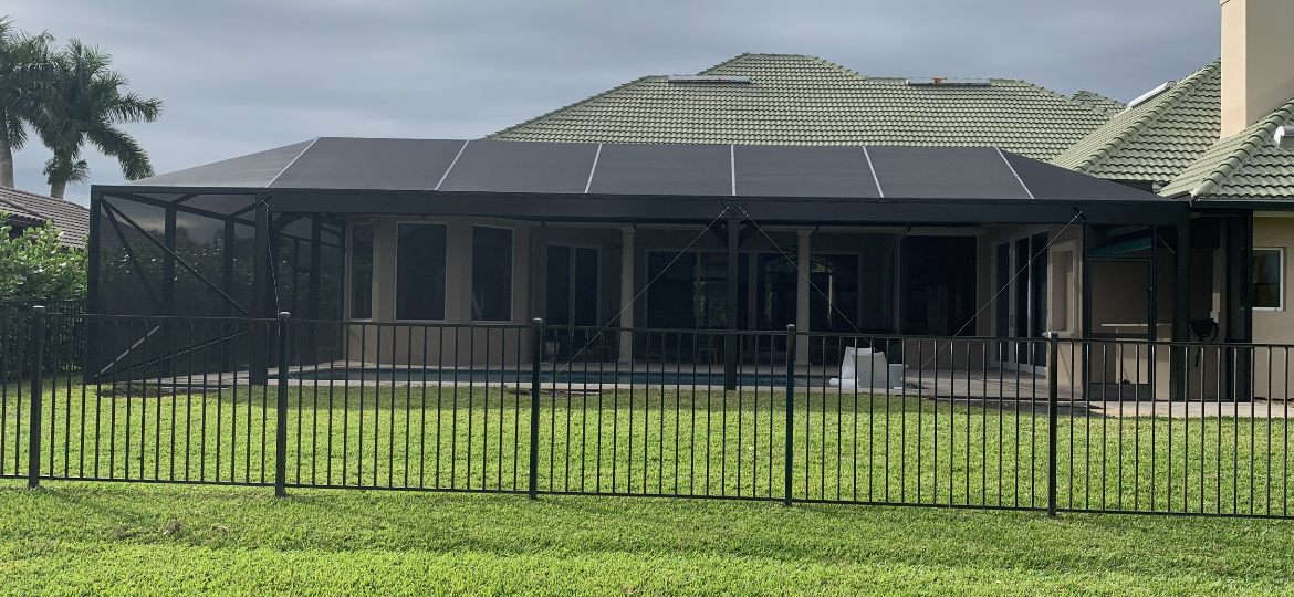 Wide aluminum screen enclosure with solid insulated roof panels over a pool deck